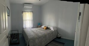 A bedroom with a bed, a nightstand, a globe, and a window with curtains. - 2-bedroom apartment in the heart of Pensacola Roatan with cool ocean breeze (Roatan)