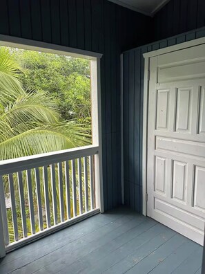 A room with a white door and a window overlooking a lush green garden. - 2-bedroom apartment in the heart of Pensacola Roatan with cool ocean breeze (Roatan)