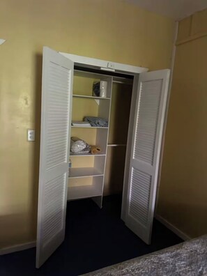 A walk-in closet with open doors, shelves, and a small storage area. - 2-bedroom apartment in the heart of Pensacola Roatan with cool ocean breeze (Roatan)