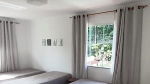 Ein Zimmer mit zwei Betten, einem Vorhangfenster und einer Deckenleuchte.