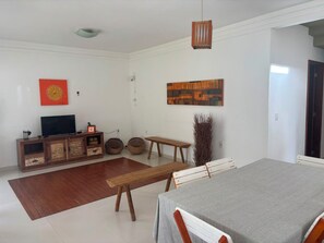 A living room with a TV, wooden furniture, and artwork on the walls.