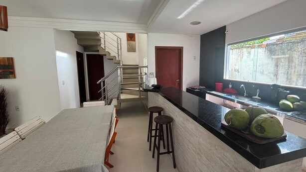 Eine moderne Küche mit Marmorarbeitsplatte, ein Essbereich mit Tisch und Stühlen sowie eine Treppe, die zu einer oberen Etage führt.