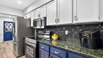 A modern kitchen with stainless steel appliances, a microwave, a coffee maker, and a blue door.
