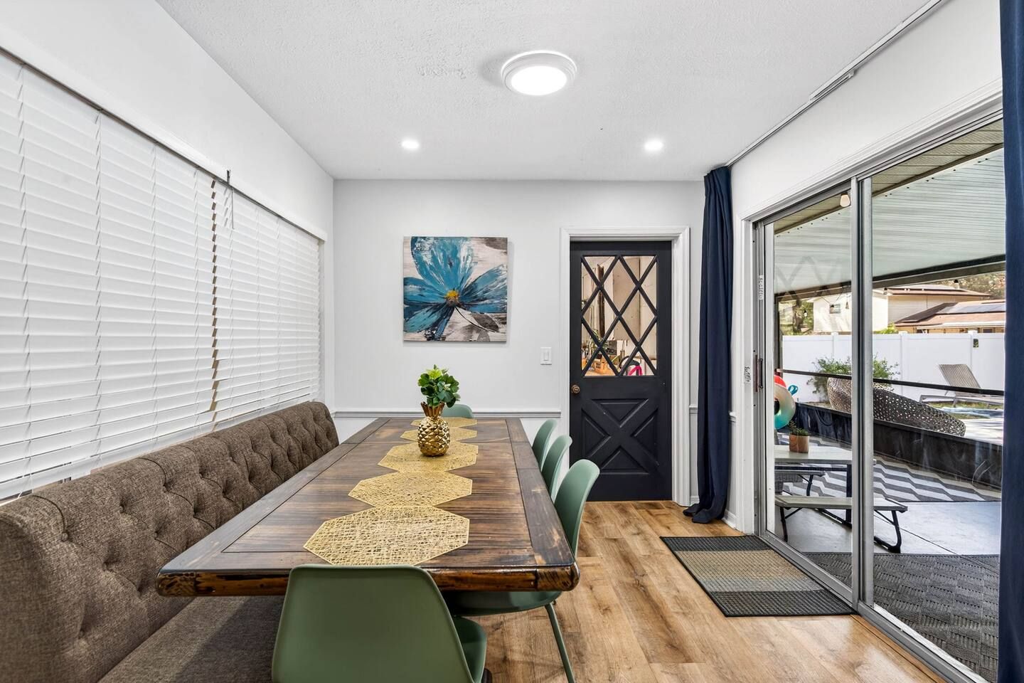 A conference room with a long table, green chairs, a decorative pineapple centerpiece, and a large abstract painting on the wall.