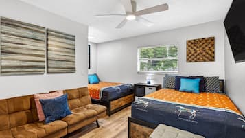 A bedroom with a bed, a sofa, a desk, and a ceiling fan.