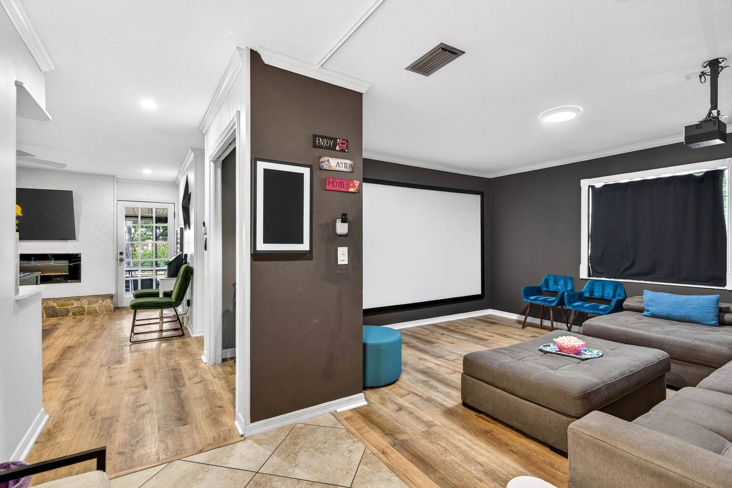 A modern living room with a fireplace, a large screen, and seating area.