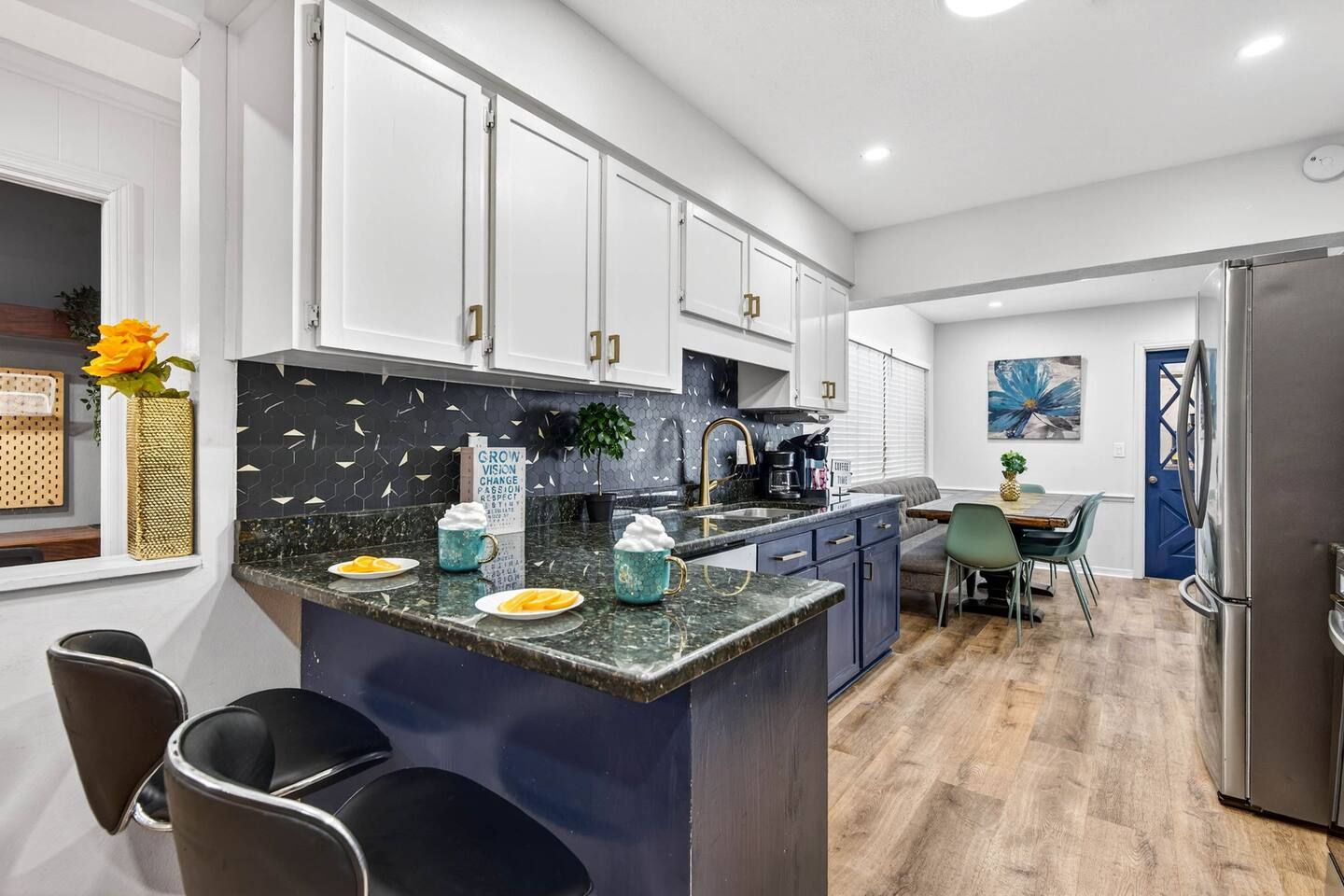 A modern kitchen with white cabinets, a granite countertop, and a central island with bar stools.