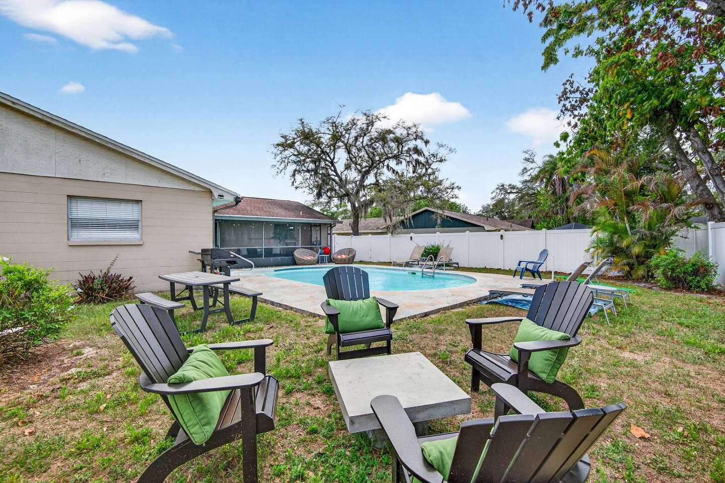A backyard with a swimming pool, outdoor seating, and a covered patio area.