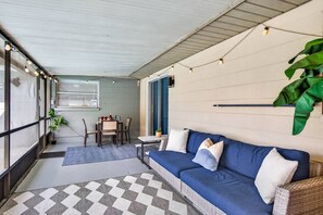 Een gezellig interieur met een bank, eettafel en stoelen, met een geruit tapijt en lichtslingers.