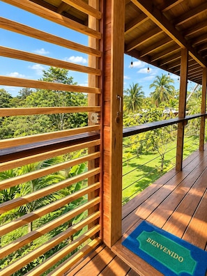 Deck de madeira com vista para vegetação exuberante e céu claro.