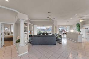 A spacious living area with a sofa, TV, and a dining area with chairs and a table. - Casa Di Sorrento Gulf Access (Cape Coral)