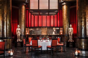 A restaurant with a central round table surrounded by red chairs, flanked by two stone statues, and red curtains. - Grand Luxxe 3BR Presidential Villa at Vidanta Available At Christmas (Nuevo Nayarit)