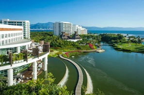 Ein modernes Hotel mit Blick auf einen Fluss, eine Brücke und üppigem Grün.