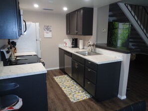 A compact kitchen with a built-in stove, a sink, and dark cabinetry.