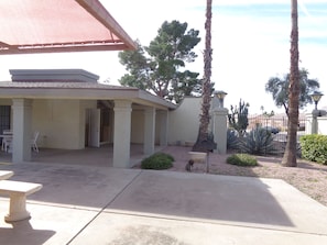 A covered patio area with a concrete floor, a table, and chairs.