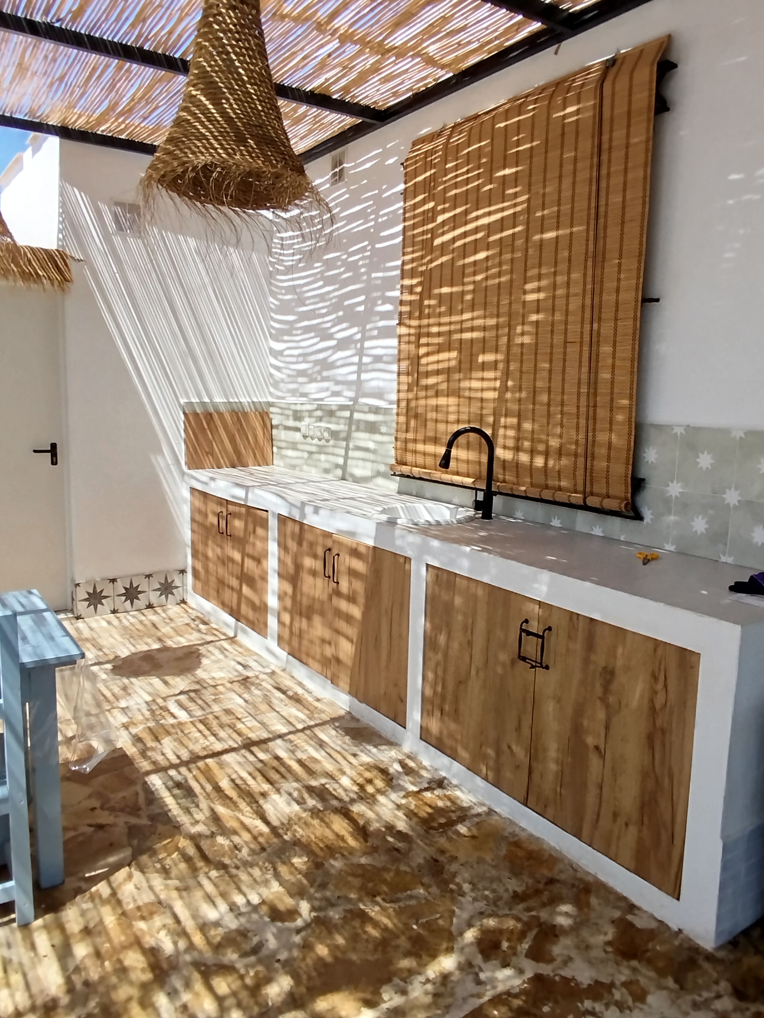 Une cuisine moderne avec des meubles en bois, un plan de travail blanc et un robinet noir.