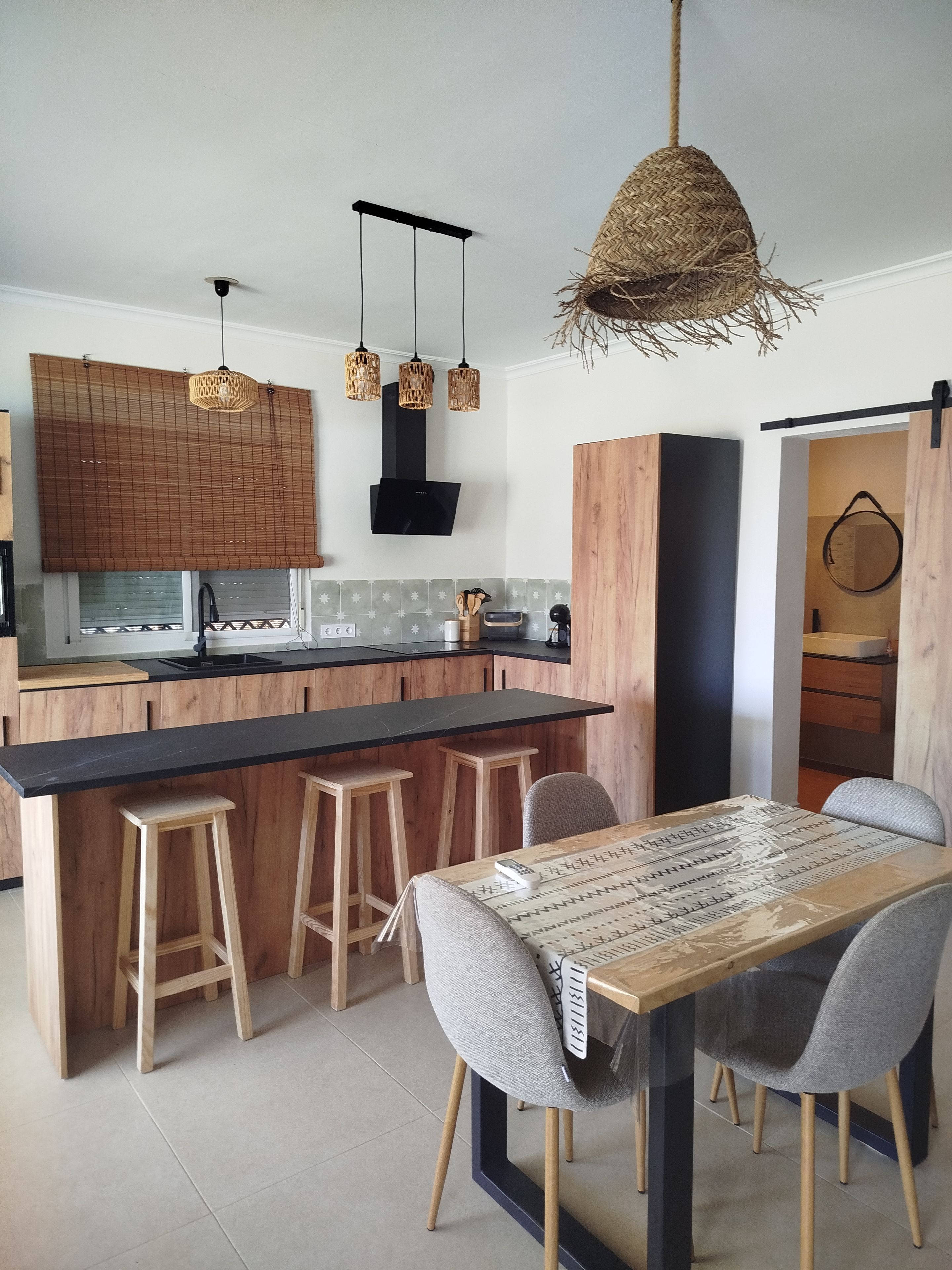 Une cuisine moderne dotée d’un îlot central, de tabourets en bois et d’une table à manger avec des chaises.