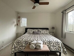 A bedroom with a bed, a ceiling fan, a window, and a bedside table with a lamp. - Secluded Catskills Retreat w/ Hot Tub & Views (Jewett)
