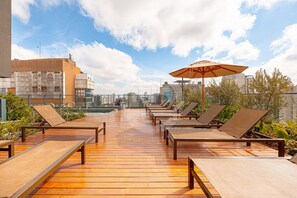 Eine Dachterrasse mit Liegestühlen und einem Pool mit Blick auf eine Stadtlandschaft.