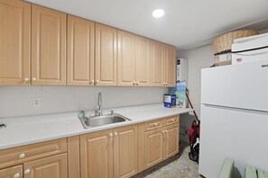 A kitchen with wooden cabinets, a stainless steel sink, and a white countertop. - Waterfront Fort Myers Beach Retreat (Fort Myers Beach)