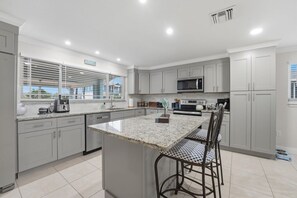 A modern kitchen with a central island, stainless steel appliances, and a view to the outside. - Waterfront Fort Myers Beach Retreat (Fort Myers Beach)