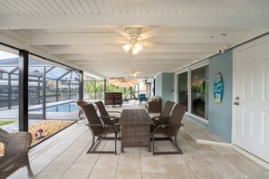 Un patio couvert avec une piscine, du mobilier d’extérieur et un ventilateur de plafond.