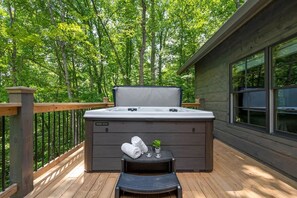 Ein Whirlpool auf einer Holzterrasse mit Blick auf einen Wald.