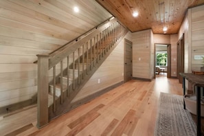A wooden interior with a staircase, a dining area, and a view through an open door. - Lux Cabin, Hot Tub, Arcade, In and Out Fireplaces (Sevierville)