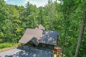 A cabin with a sloped roof, surrounded by dense forest. - Lux Cabin, Hot Tub, Arcade, In and Out Fireplaces (Sevierville)