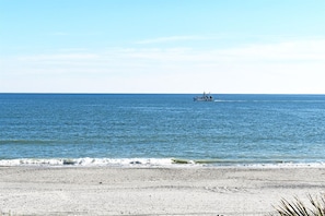 A beach with a boat in the distance and a clear sky. - Wonderful 3  bedroom Unit at Sand Dunes Resort (Myrtle Beach)