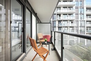 Un balcon avec deux chaises en bois, une petite table et une plante en pot.