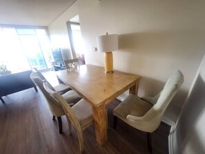A dining area with a wooden table and four chairs, a lamp, and a view of the outdoors. - 2-bedroom condo in soothing Honolulu with AC and fitness room (Honolulu)