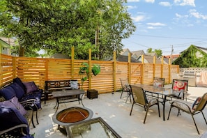 Eine Terrasse mit Tisch, Stühlen, einer Bank und einem Grill.