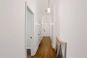 A hallway with white walls, wooden flooring, and a ceiling light fixture. - Spacious Herron-Morton Stay Near Downtown (Indianapolis)