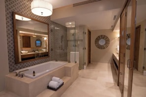 Ein modernes Badezimmer mit einer großzügigen Badewanne, einer Duschkabine und einem runden Spiegel mit Zierdekor.