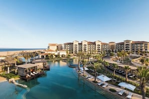 A resort with a central swimming pool, multiple hotel buildings, and palm trees. - Spend Halloween in Cabo 2br/3bth condo Oct 31- Nov 7 (Cabo San Lucas)