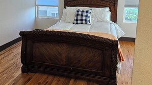 Een slaapkamer met een groot bed, houten vloer en een kroonluchter.