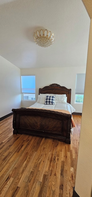 Une chambre à coucher avec un grand lit, un plancher en bois et un lustre.