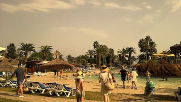 Ein Strandhotel mit Liegestühlen, Palmen und einem Poolbereich.