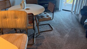 Ein Wohnzimmer mit rundem Tisch, Stühlen, einem Fernseher und Blick durch die Glastür.