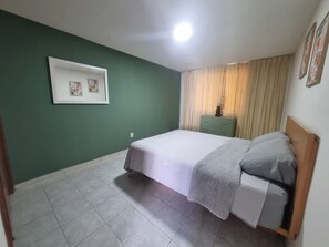 Un dormitorio con cama, mesita de noche, cómoda y un cuadro enmarcado en la pared.