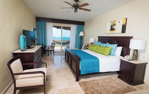 Habitación de hotel con cama, escritorio, silla, televisión y vista al océano.