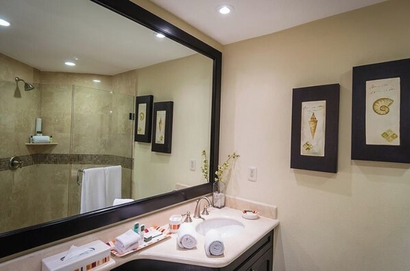 Un baño de hotel con un espejo grande, un lavamanos y cuadros en la pared.