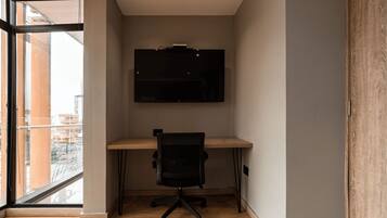 A modern office space with a desk, chair, and a mounted flat-screen TV.