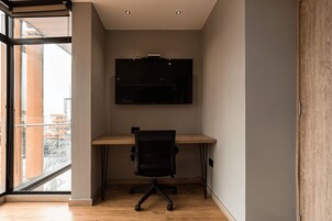 Un espacio de oficina moderno con escritorio, silla y un televisor de pantalla plana montado.