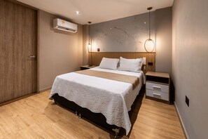 Un dormitorio moderno con una cama, mesitas de noche, un armario de madera y un equipo de aire acondicionado.