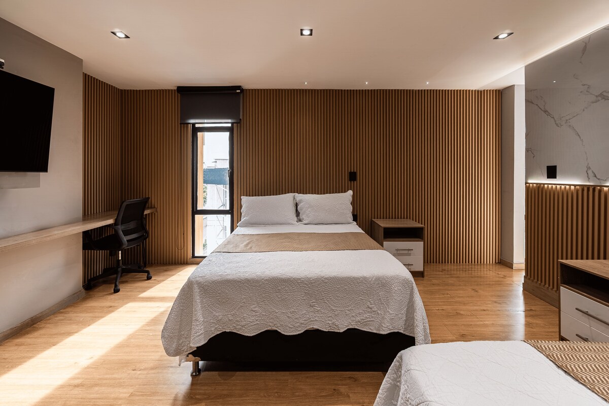 A modern bedroom with a large bed, a desk, and a TV.