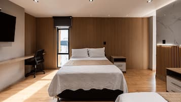 Un dormitorio moderno con una cama grande, un escritorio y un televisor.