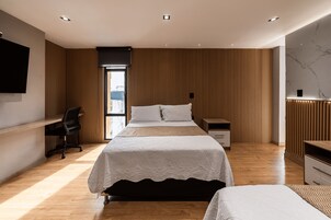 Un dormitorio moderno con una cama grande, un escritorio y un televisor.