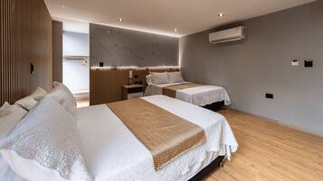 Una habitación de hotel moderna con dos camas, piso de madera, pared de mármol y unidad de aire acondicionado.